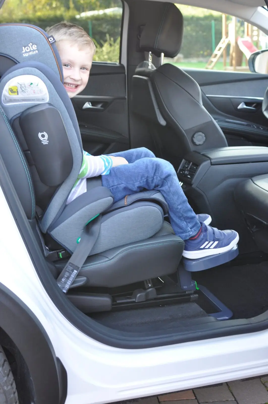 Usměvavý chlapec v autosedačce má nohy opřené o podnožku