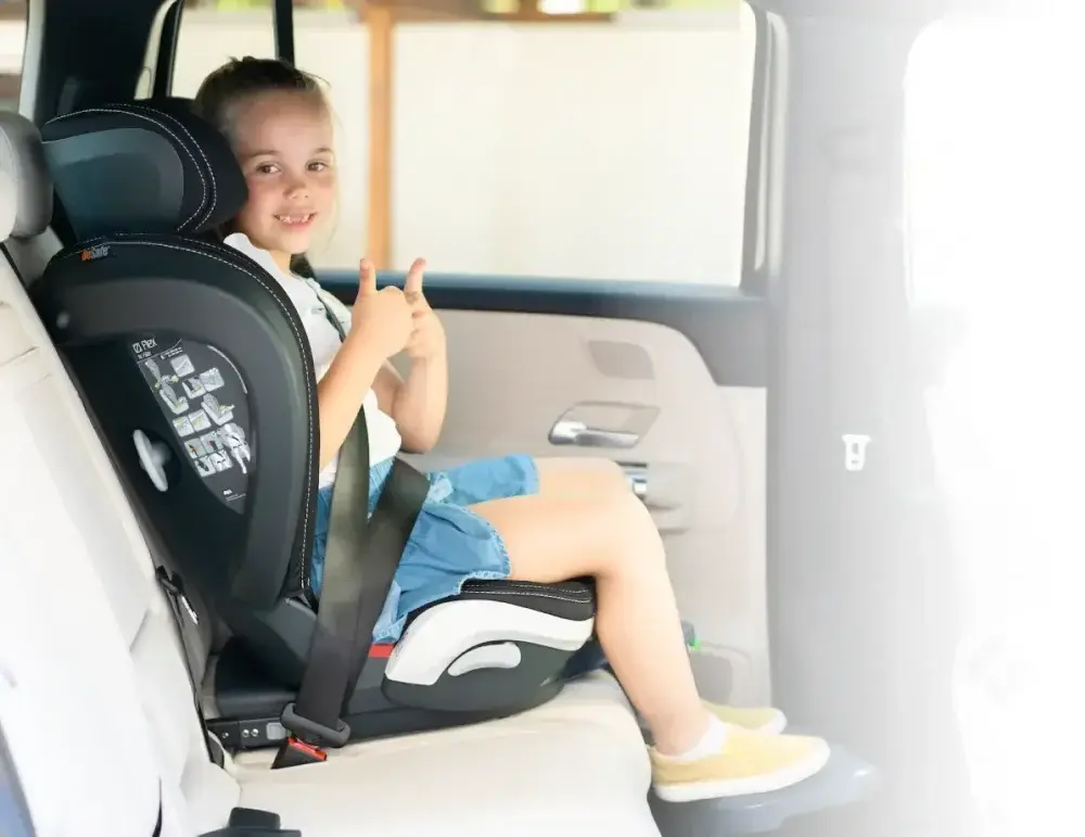Usměvavá holčička v autosedačce ukazuje palce nahoru